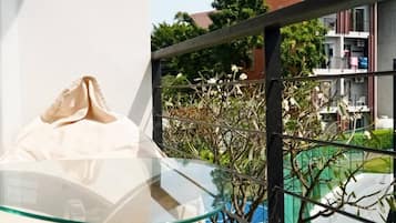 A glass table with a white object on it, a metal railing, and a view of a building with balconies and greenery.