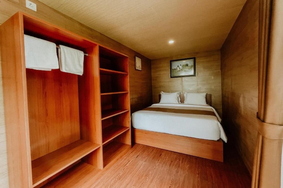 Ein Schlafzimmer mit einem Holfischschrank, einem Bett und einem Bild an der Wand.