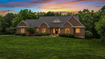 A two-story brick house with a gabled roof, a front porch, and a well-maintained lawn.