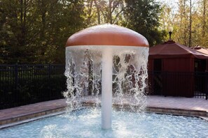 A fountain with water jets in a circular pool, surrounded by a fence and trees. - Sunshine Getaway at Tuscana Resort (Davenport)