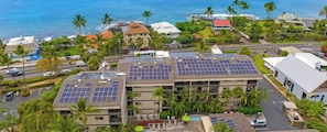 A multi-story building with solar panels on the roof, surrounded by palm trees and a view of the ocean. - WorldMark Kona, one of the most beautiful spots on the Big Island! (Kailua-Kona)