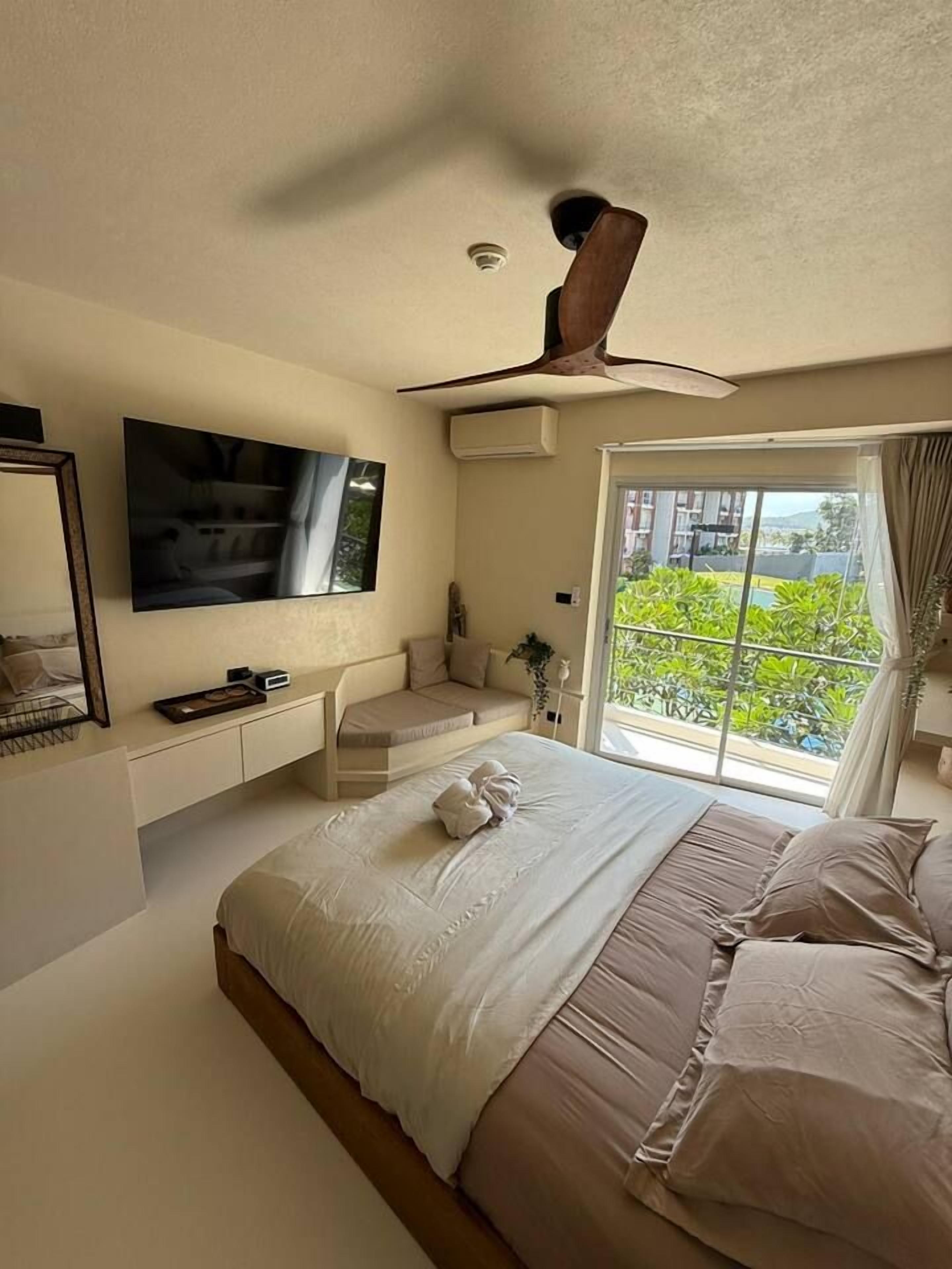 Une chambre avec un lit, une télévision, un bureau et une fenêtre donnant sur un beau paysage.