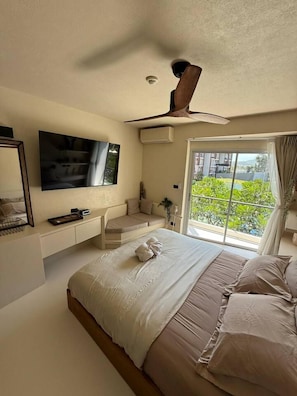 Een slaapkamer met een bed, een televisie, een bureau en een raam met uitzicht.