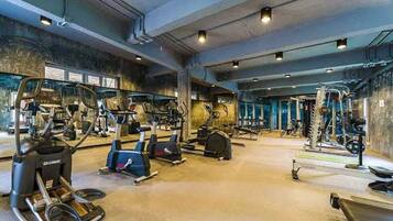 Een sportschool met diverse fitnessapparaten, waaronder loopbanden, elliptische trainers en krachtstations.