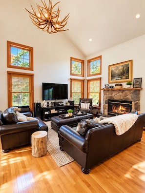 A spacious living room with a fireplace, leather sofas, a flat-screen TV, and large windows. - 4BR Poconos Retreat, Fall at Camelback (Tannersville)