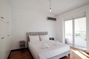 Ein Schlafzimmer mit einem Bett, einem Nachttisch, einer Wand-Klimaanlage und einem großen Fenster.