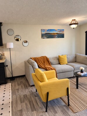 A living room with a sofa, armchair, and a painting on the wall. - The Worldhouse: A Unique Travel-Themed Stay Near Seattle (Renton)