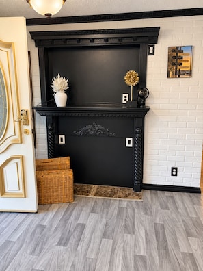 A black fireplace with a white brick wall and a door with gold detailing. - The Worldhouse: A Unique Travel-Themed Stay Near Seattle (Renton)