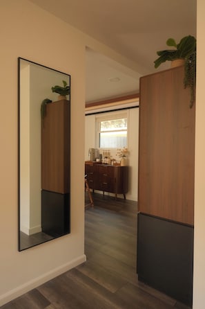 Un pasillo con un espejo grande, armarios de madera y un escritorio con ventana.