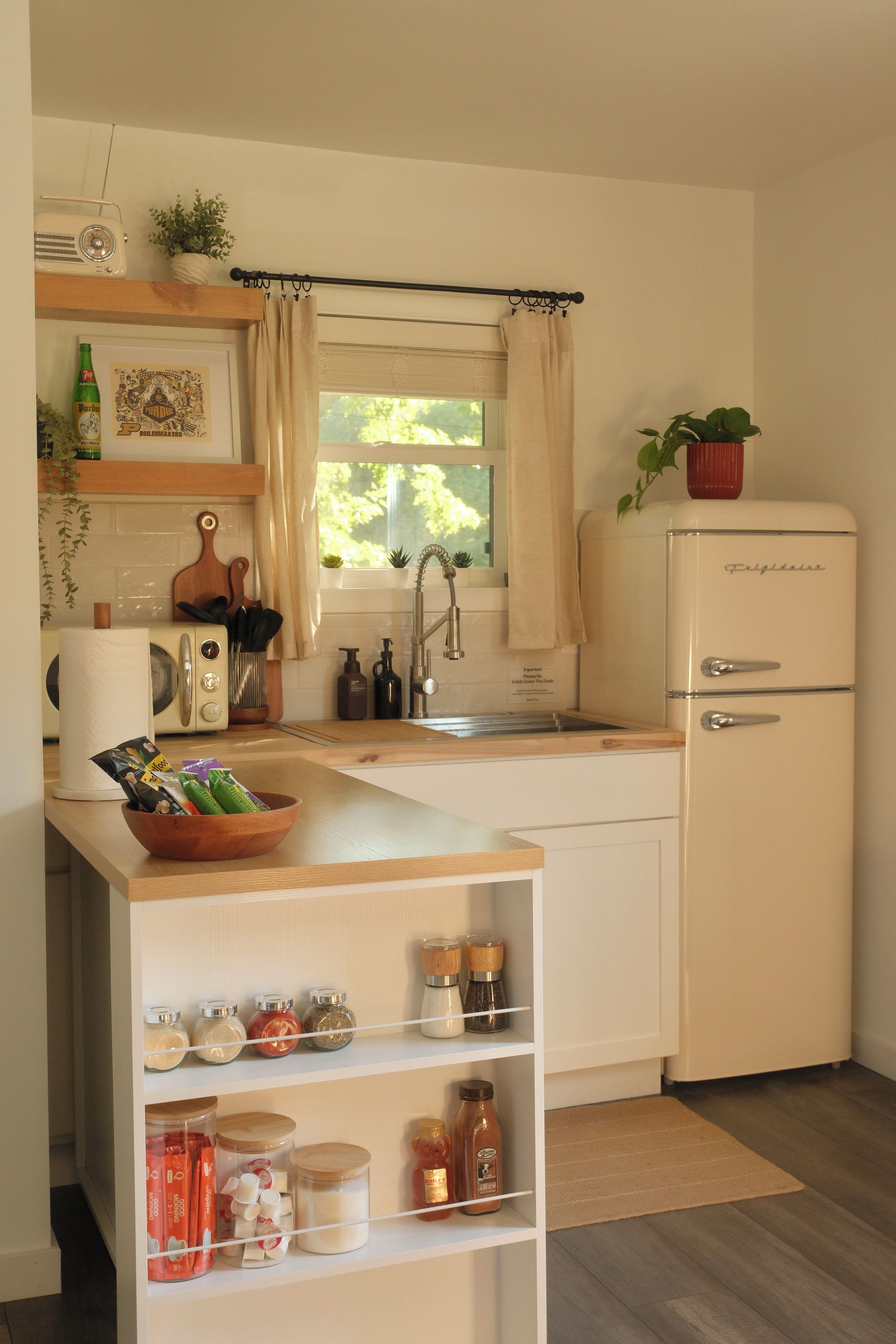 A compact kitchen with a refrigerator, sink, and wooden countertop.