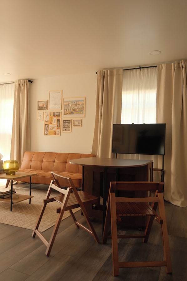 Una sala de estar con sofá, una mesa de centro, un televisor y un conjunto de cuadros en la pared.