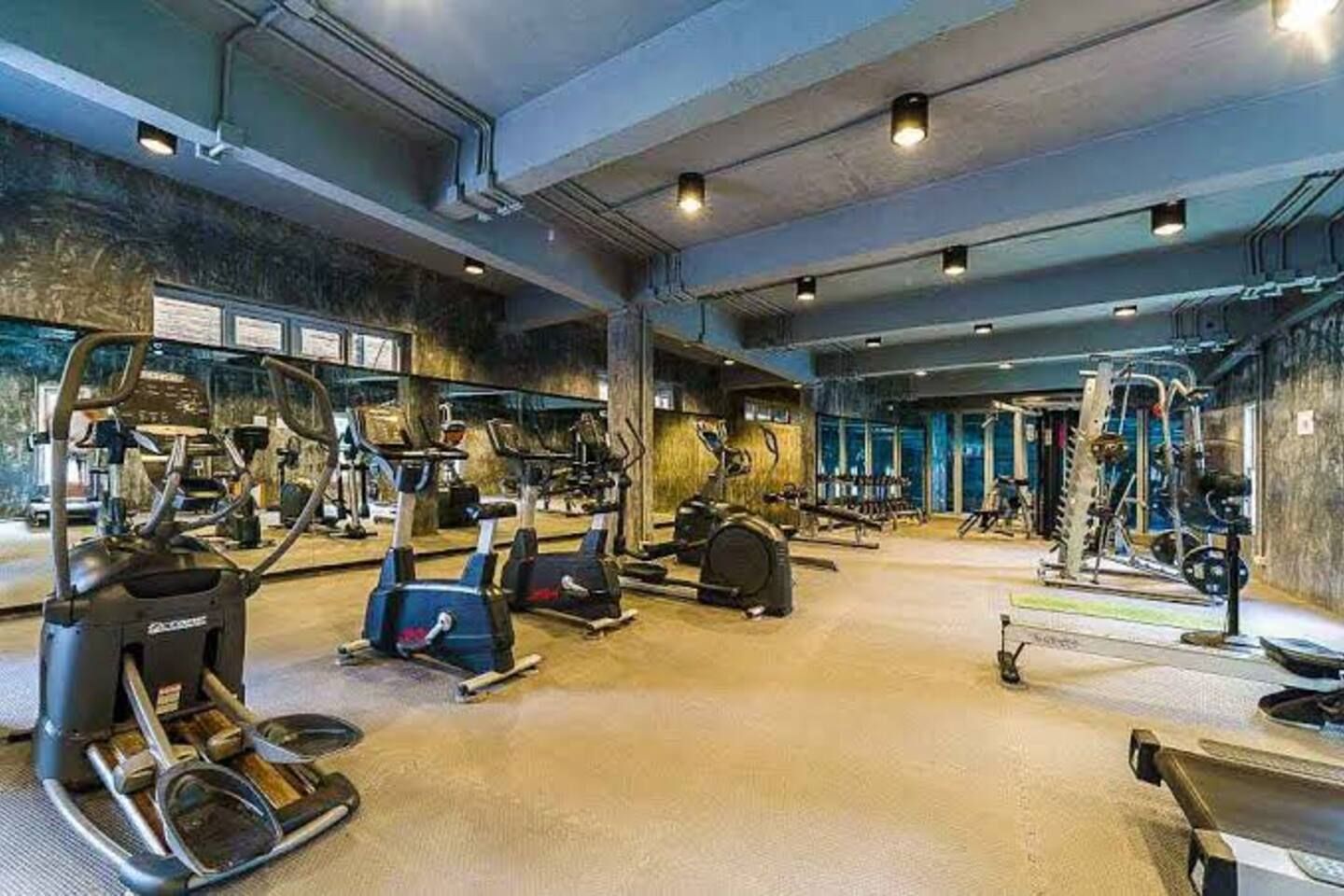 Een sportschool met diverse fitnessapparaten, waaronder loopbanden, elliptische trainers en krachtstations.