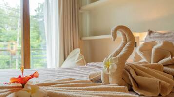 A hotel room with a bed, a window with curtains, and a towel with a flower.