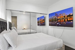 A hotel room with a large bed, a nightstand, a lamp, and a cityscape painting on the wall. - Family 5-bed House Near Tarneit Central (Melbourne)