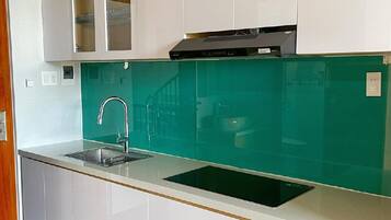 Una cocina moderna con armarios blancos, salpicadero verde y estufa integrada.