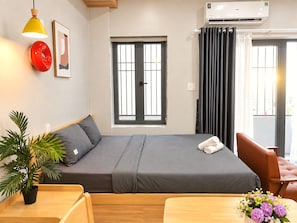 Habitación de hotel con cama, ventana, aire acondicionado, planta y una silla.
