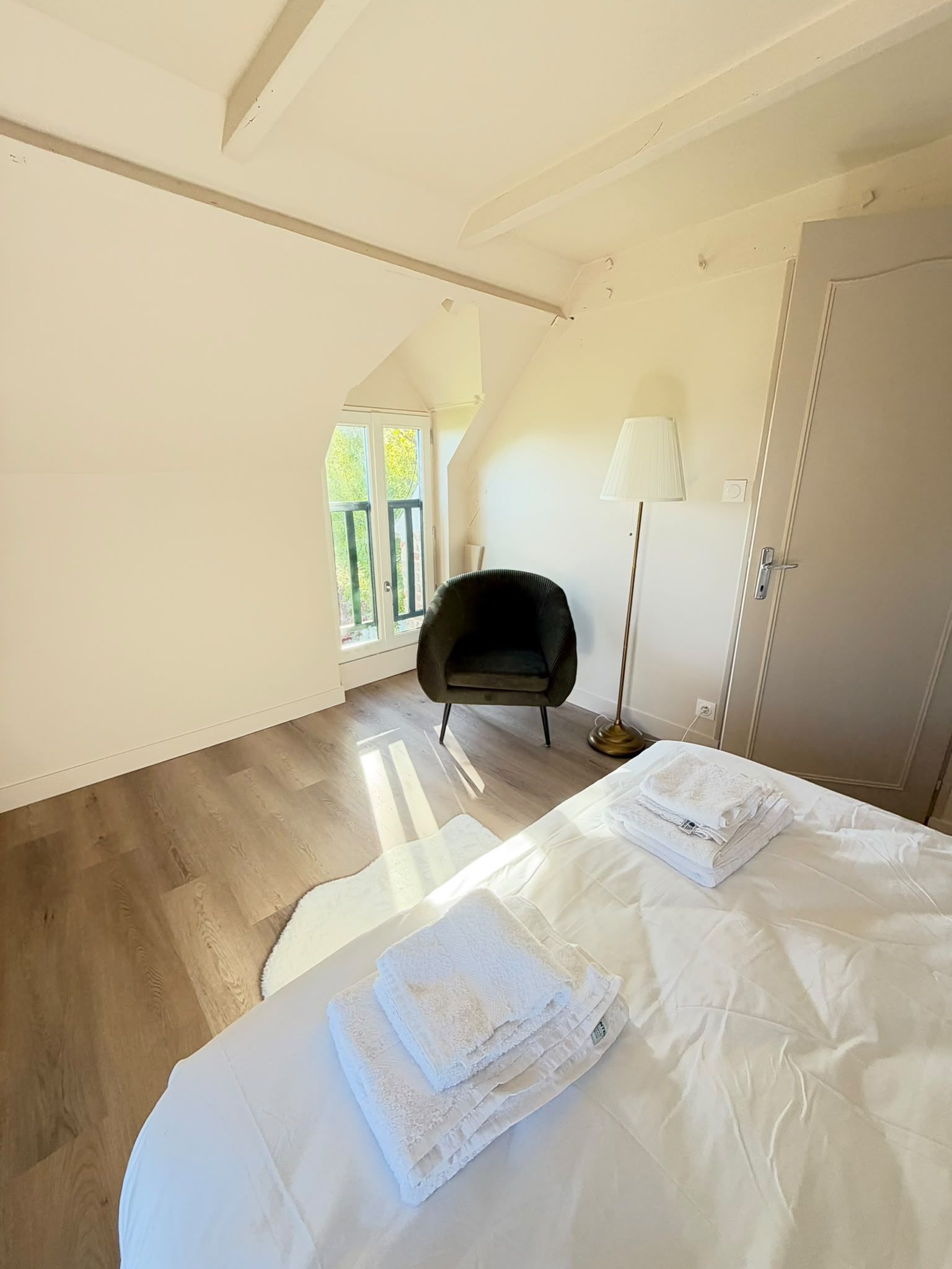 Een slaapkamer met een bed, een stoel, een lamp en een kledingkast.