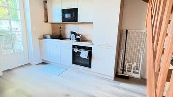 A modern kitchen with white cabinetry, a built-in oven, and a microwave.