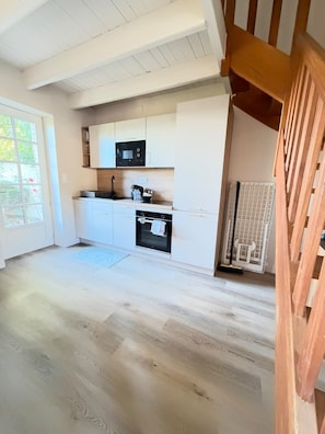 A modern kitchen with white cabinetry, a black microwave, and a built-in oven.