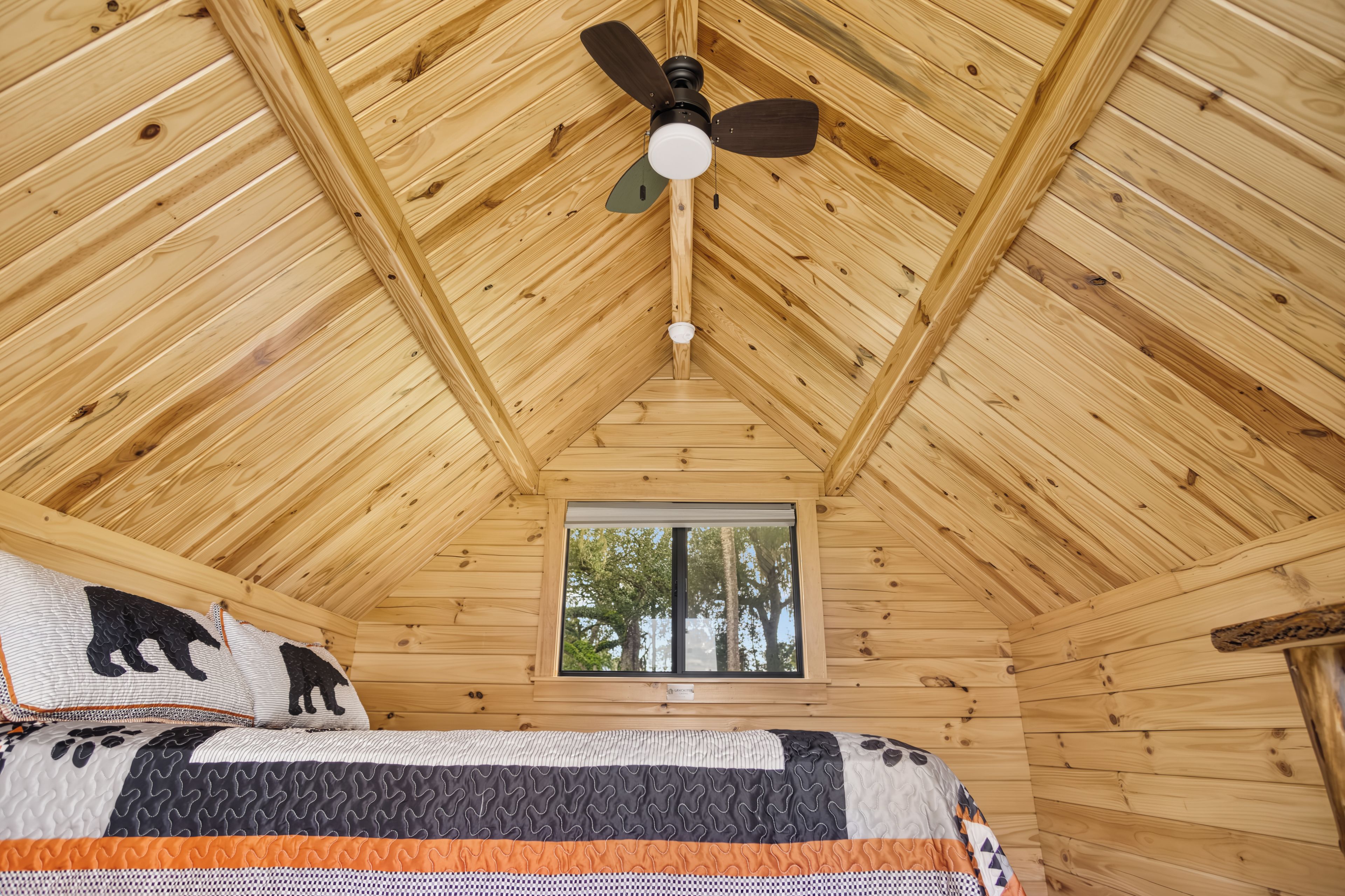Cozy wood-lined loft with tree-view window and charming cabin style