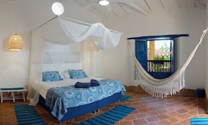 Een slaapkamer met een bed, een hangmat en uitzicht op buiten.