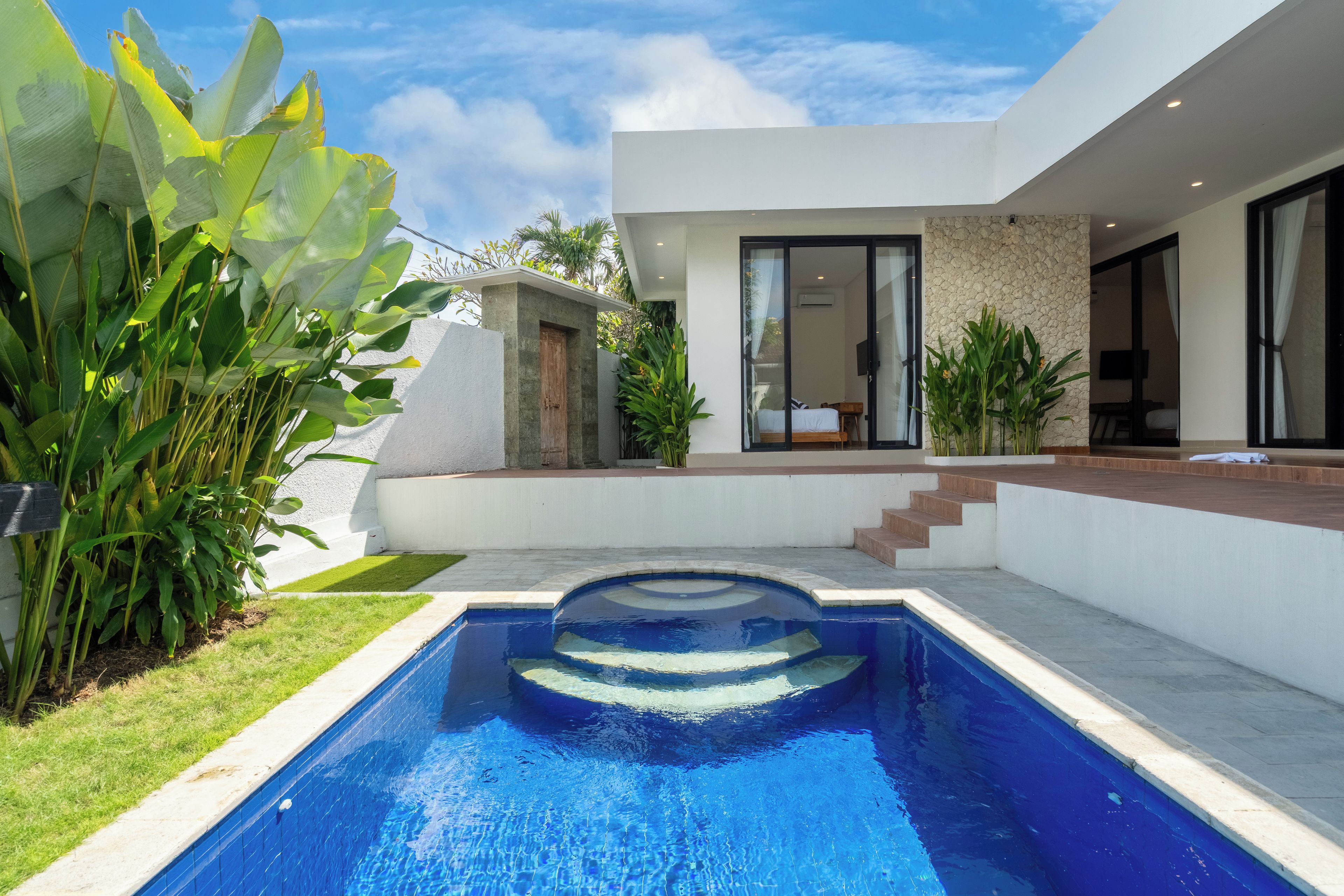 A modern house with a swimming pool, a stone wall, and a wooden door.