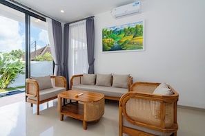 A modern living room with a sofa, two armchairs, a coffee table, and a painting of a landscape. - VILLA LITAN SEMINYAK  (Kec Kuta)