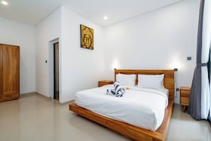 A hotel room with a wooden bed, white linens, a nightstand, a wardrobe, and a wall-mounted artwork. - VILLA LITAN SEMINYAK  (Kec Kuta)