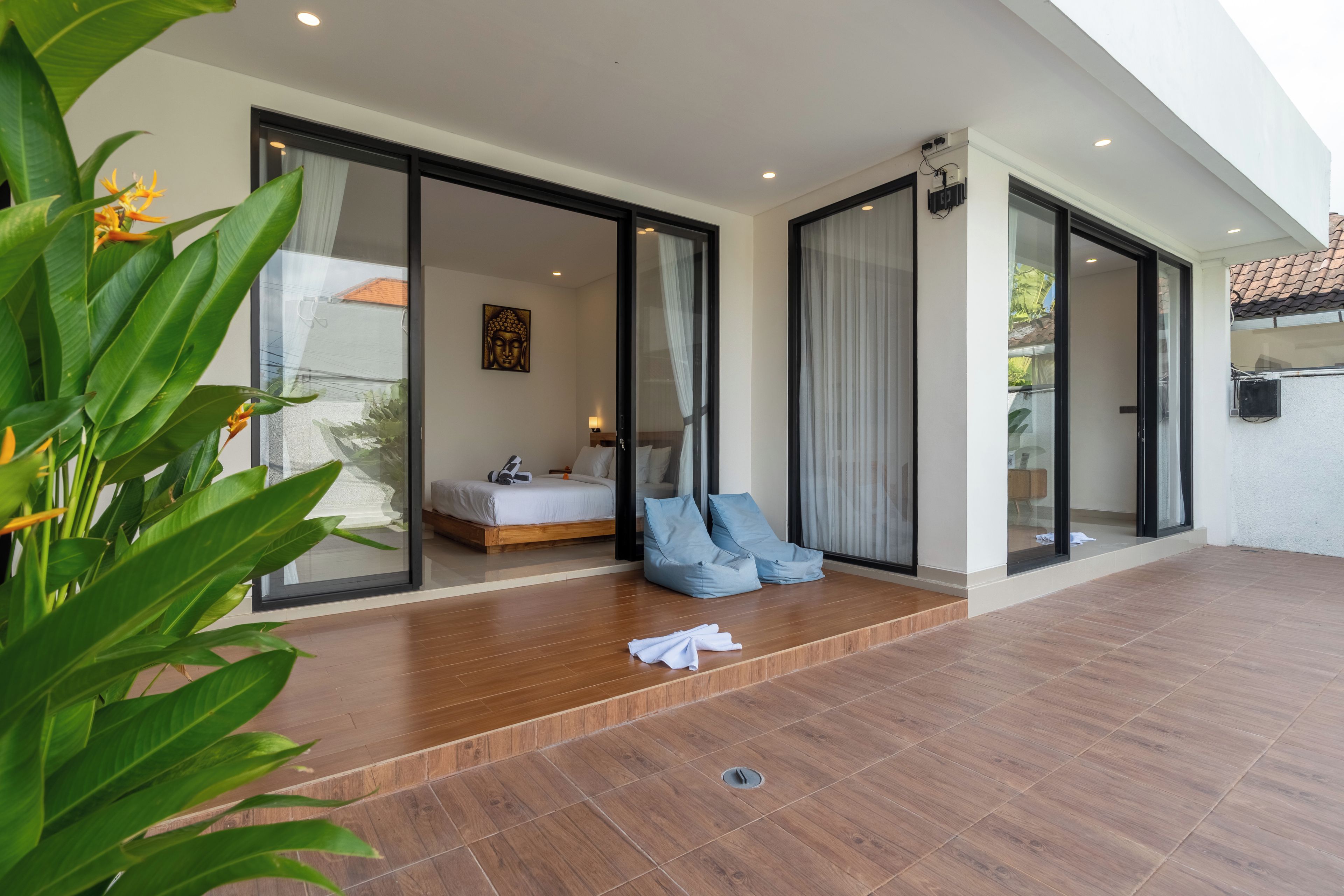 A modern interior with a wooden floor, a bed, a sofa, and a Buddha statue.
