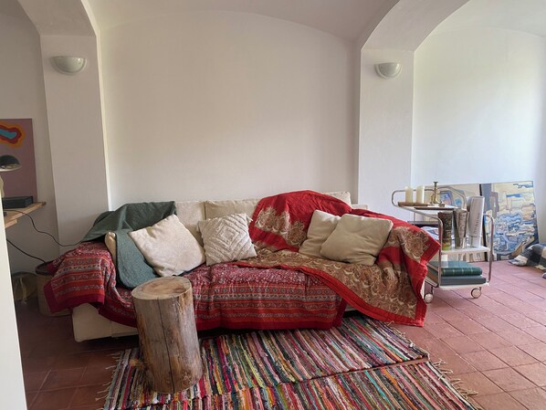 A cozy living room with a sofa, a colorful woven rug, and a wooden stool. - Vrbo Property (Buckow (Märkische Schweiz))
