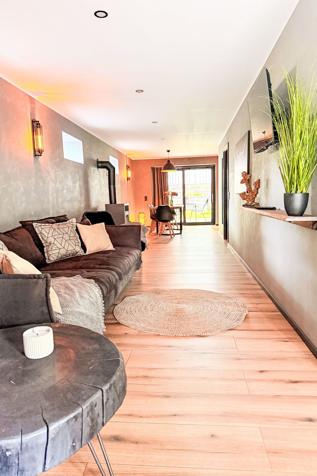 A modern living room with a sofa, a coffee table, and a dining area with chairs and a table.