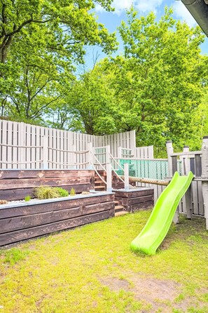 A backyard with a wooden fence, a green slide, and a wooden staircase. - Seite Deern by Interhome (Altwarp)