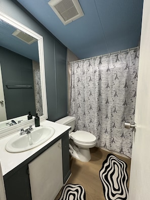 A bathroom with a white sink, a toilet, and a shower curtain with Eiffel Tower prints. - Comfortable Stay Near Downtown Austin/ The Domain (Austin)