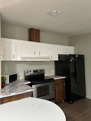 A kitchen with white cabinets, a black refrigerator, a microwave, a stove, and a sink. - Comfortable Stay Near Downtown Austin/ The Domain (Austin)