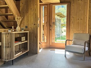 A wooden interior with a chair, a shelf with books, and a door leading outside. - The Stalluccia by Interhome (Stampa)