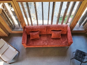A room with a wooden-framed window, a red sofa with cushions, a white chair, and a tiled floor. - The Stalluccia by Interhome (Stampa)