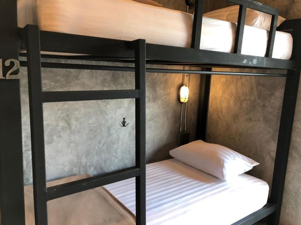 A bunk bed with a white mattress and a single bed with a white pillow.