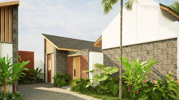 A modern residential building with a paved entrance, a brick entrance, and a variety of tropical plants.