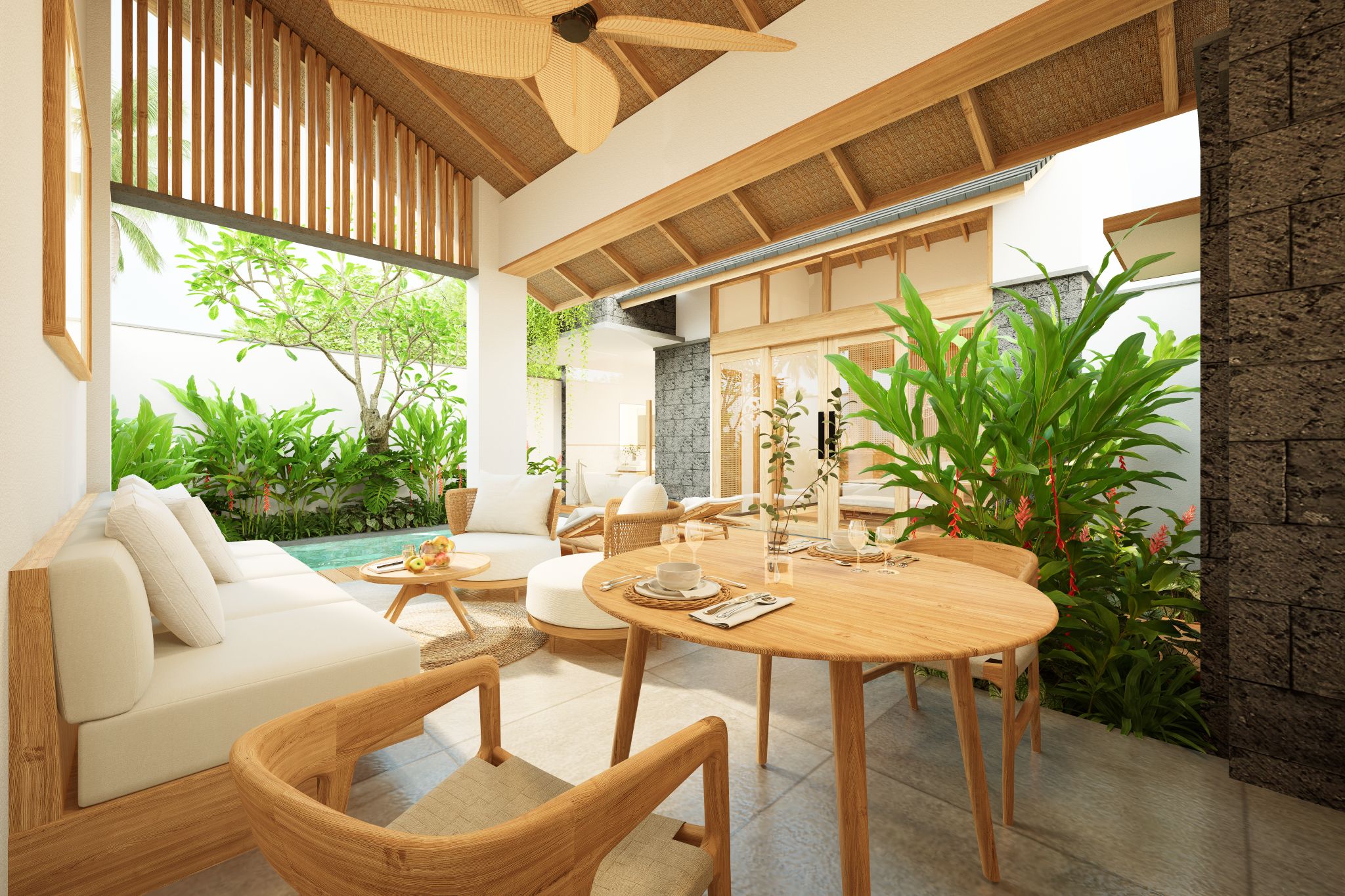 A modern outdoor living area with a round wooden table, wicker furniture, and a view of a pool and greenery.