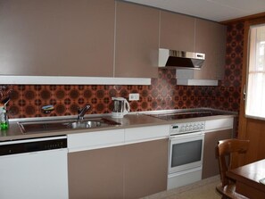 A modern kitchen with a dishwasher, stove, and a kettle on the countertop. - Däpp # 2 Appartement/Fewo, Dusche oder Bad, WC, 2 Schlafräume 4-Bett-Wohnung by Interhome (Lenk)