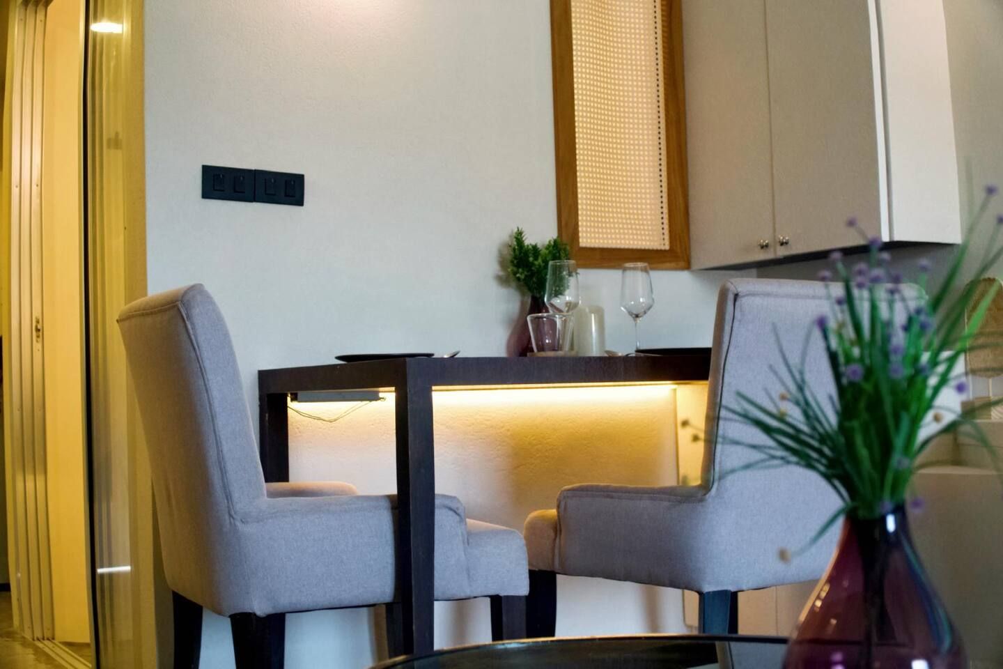 A dining area with two chairs, a table, and a vase with flowers.