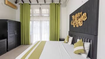 Ein Hotelzimmer mit einem Bett, grünen Vorhängen, einer Wanddekoration und einer Holzbalkendecke.