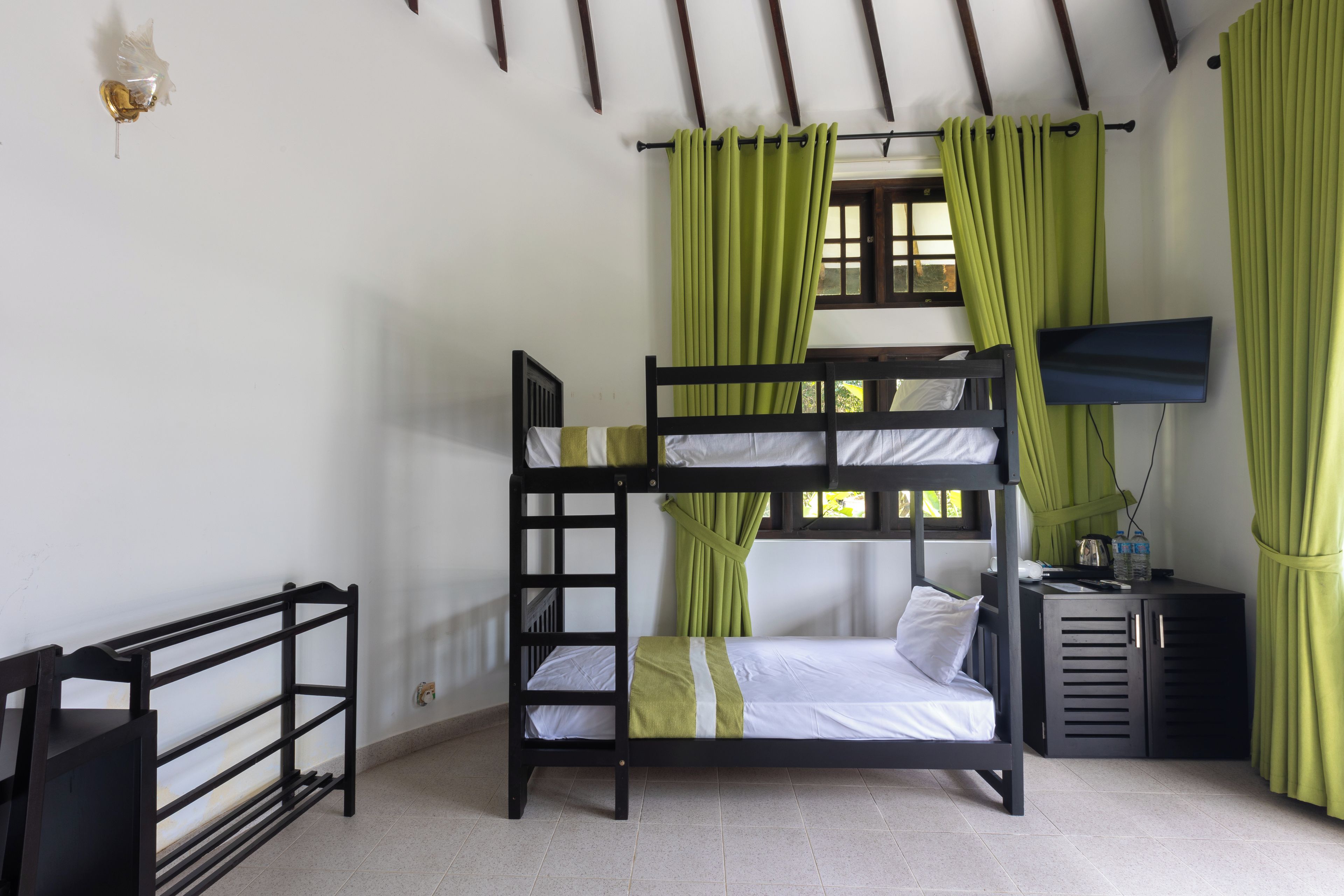 Camera con letto a castello, televisione, scrivania e finestra con tende.