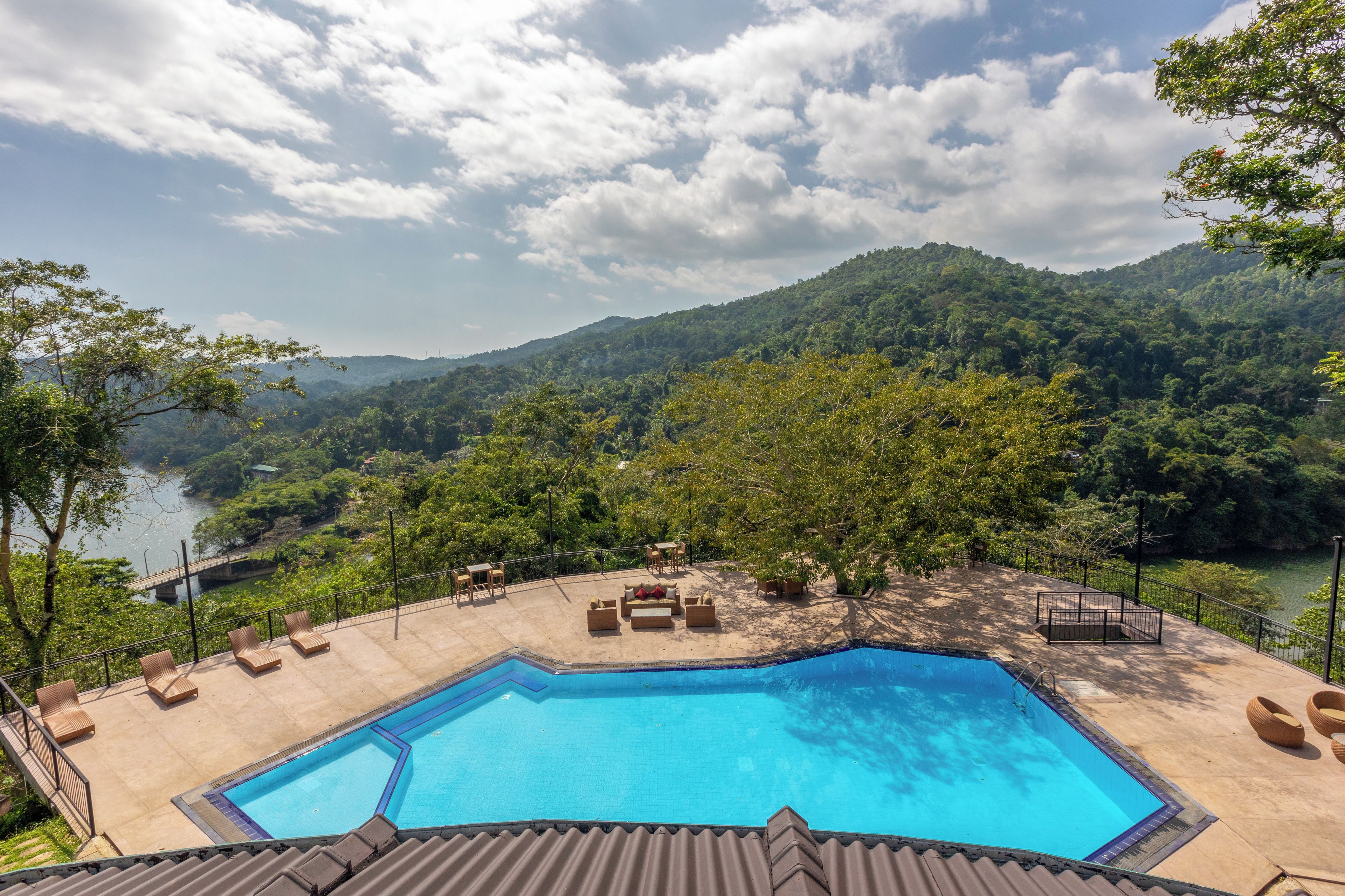 Un espace piscine avec des chaises longues et une vue sur une rivière et des montagnes.