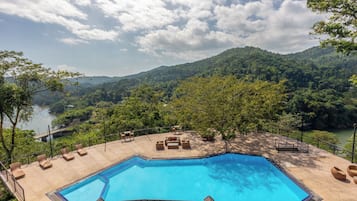 Ein Poolbereich mit Liegestühlen und Blick auf einen Fluss und Berge.