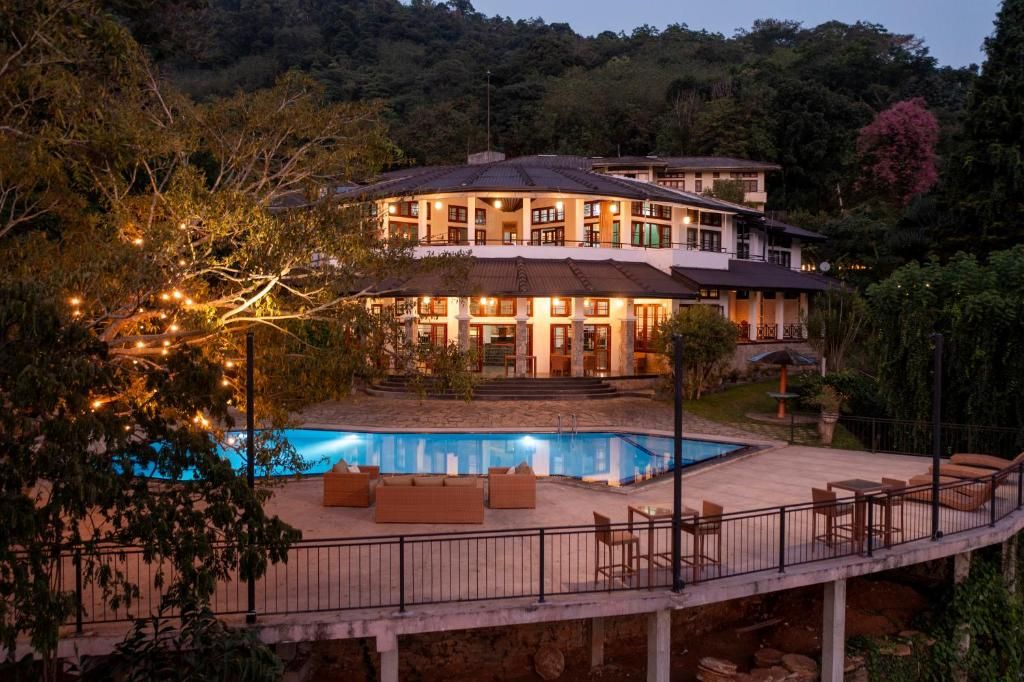 Un edificio grande de varios pisos con piscina, mobiliario exterior y una zona de balcón bien iluminada.