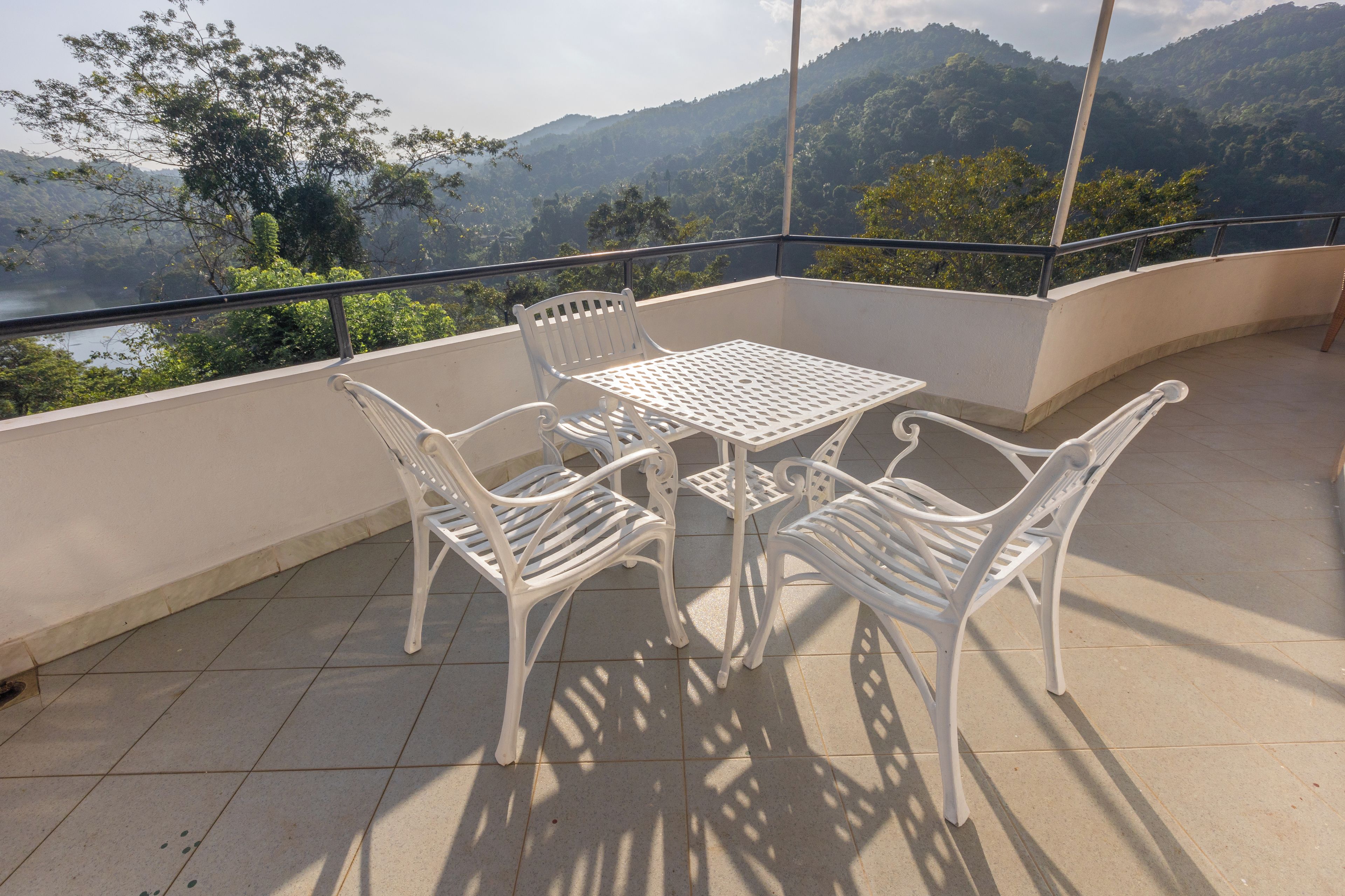 Een balkon met een tafel en stoelen, met uitzicht op een bergachtig landschap.