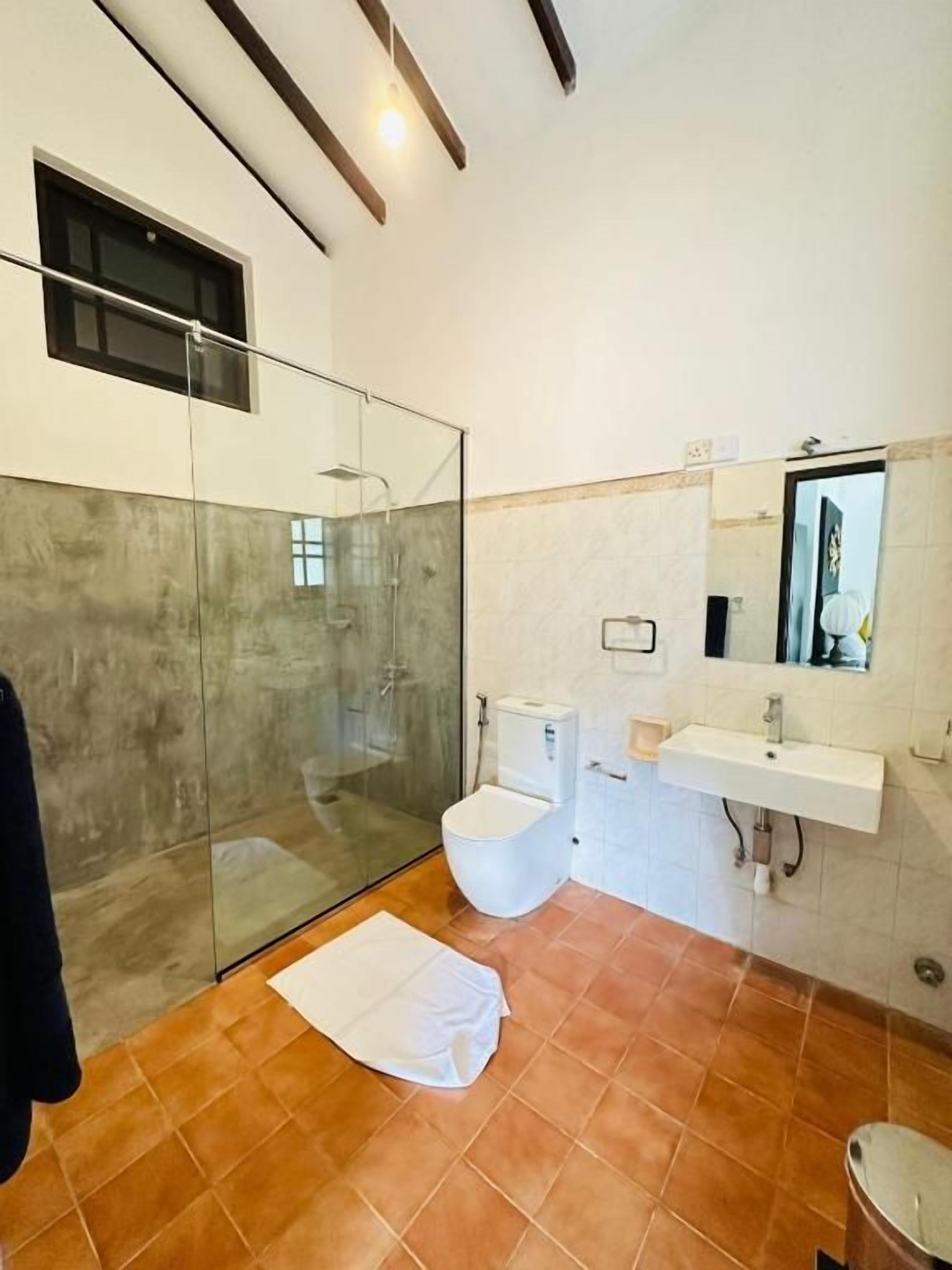 Un bagno moderno con cabina doccia in vetro, un water e un lavandino.