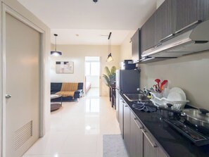 A modern kitchen with a built-in stove, a sink, and a refrigerator. There is a dining area with a sofa and a table in the background.
