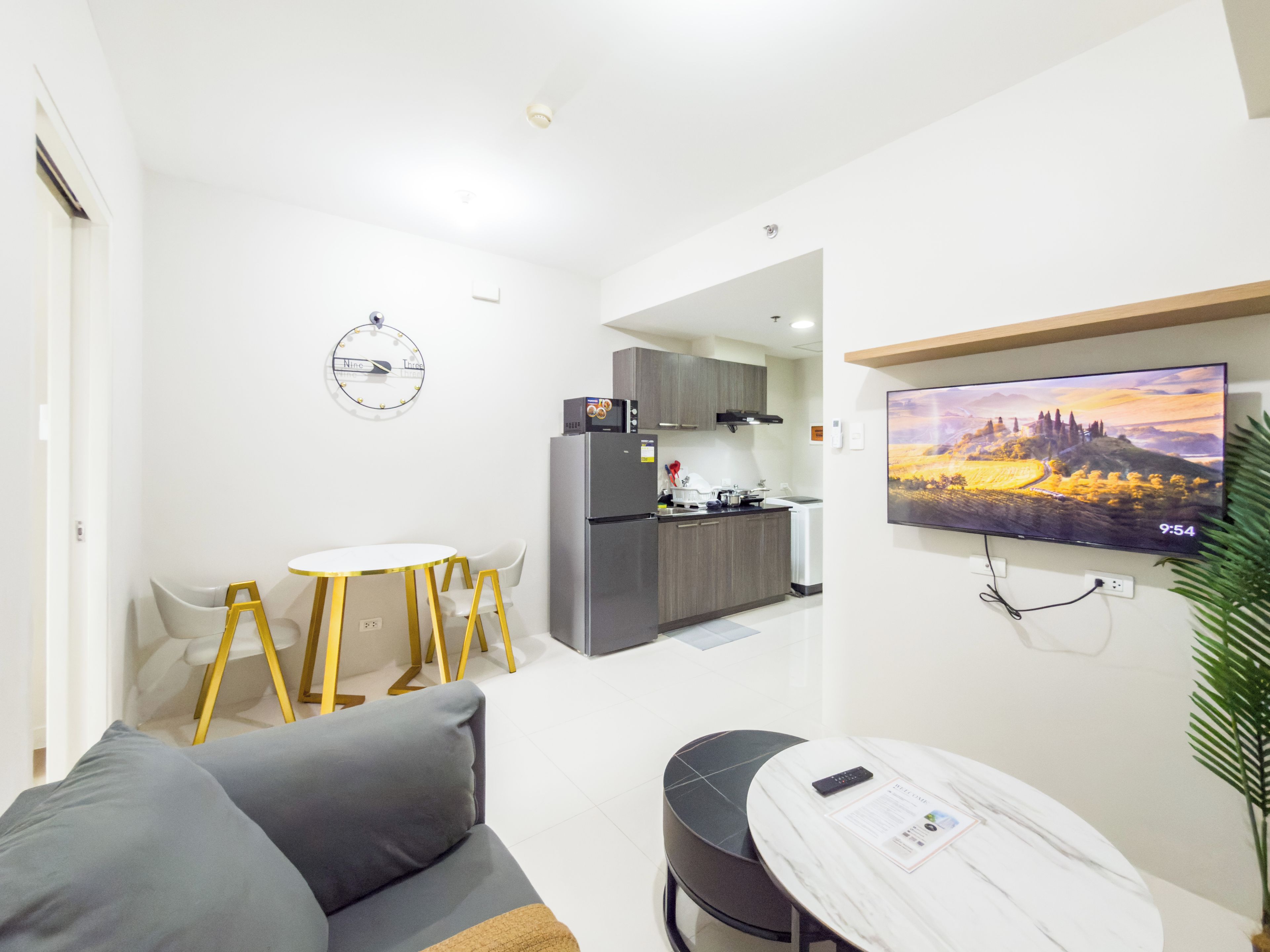 Un espacio habitable compacto con kitchenette, una zona de comedor y una sala de estar con un televisor montado en la pared.